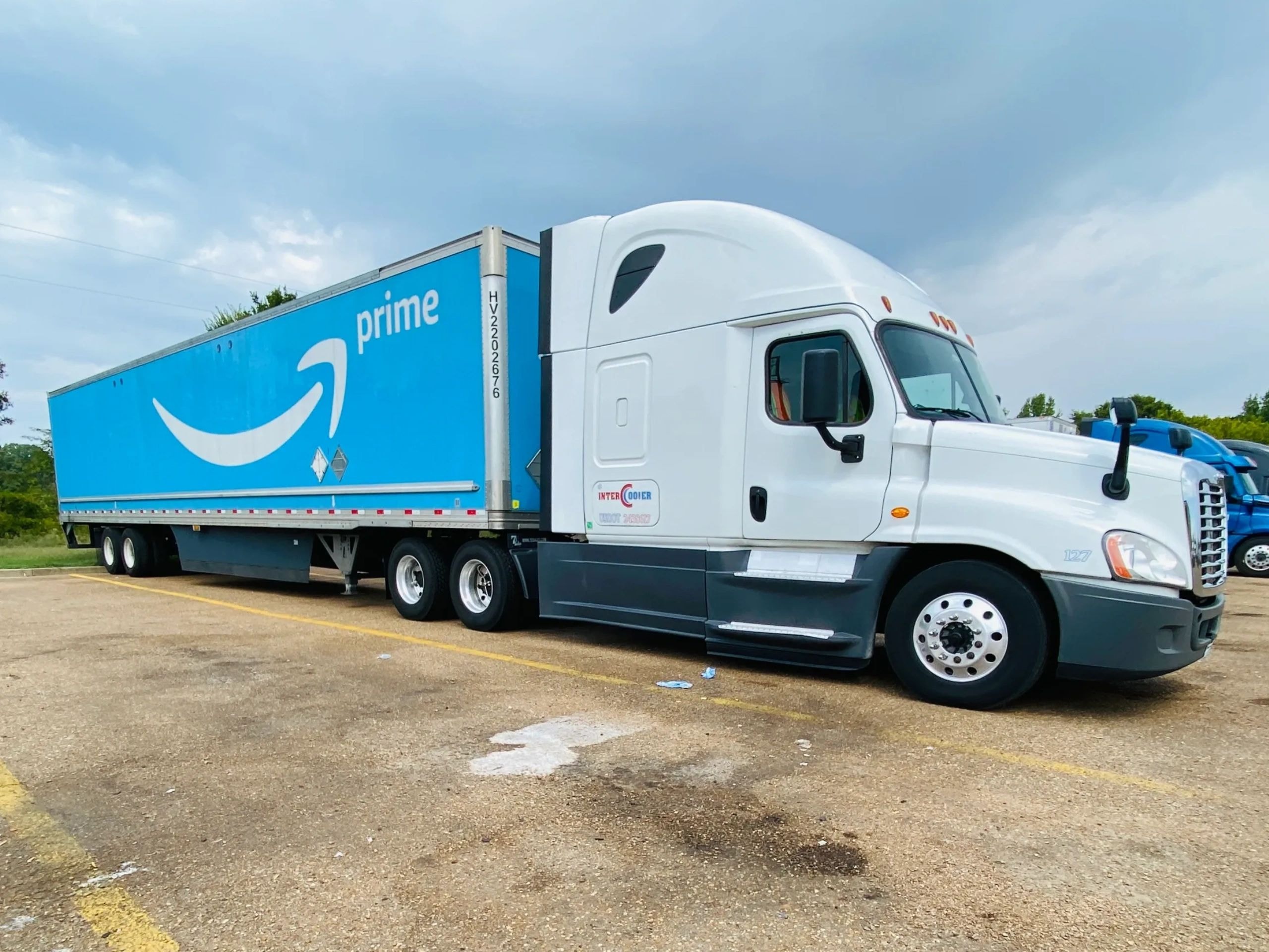 White Freightliner semi-truck with delivery trailer